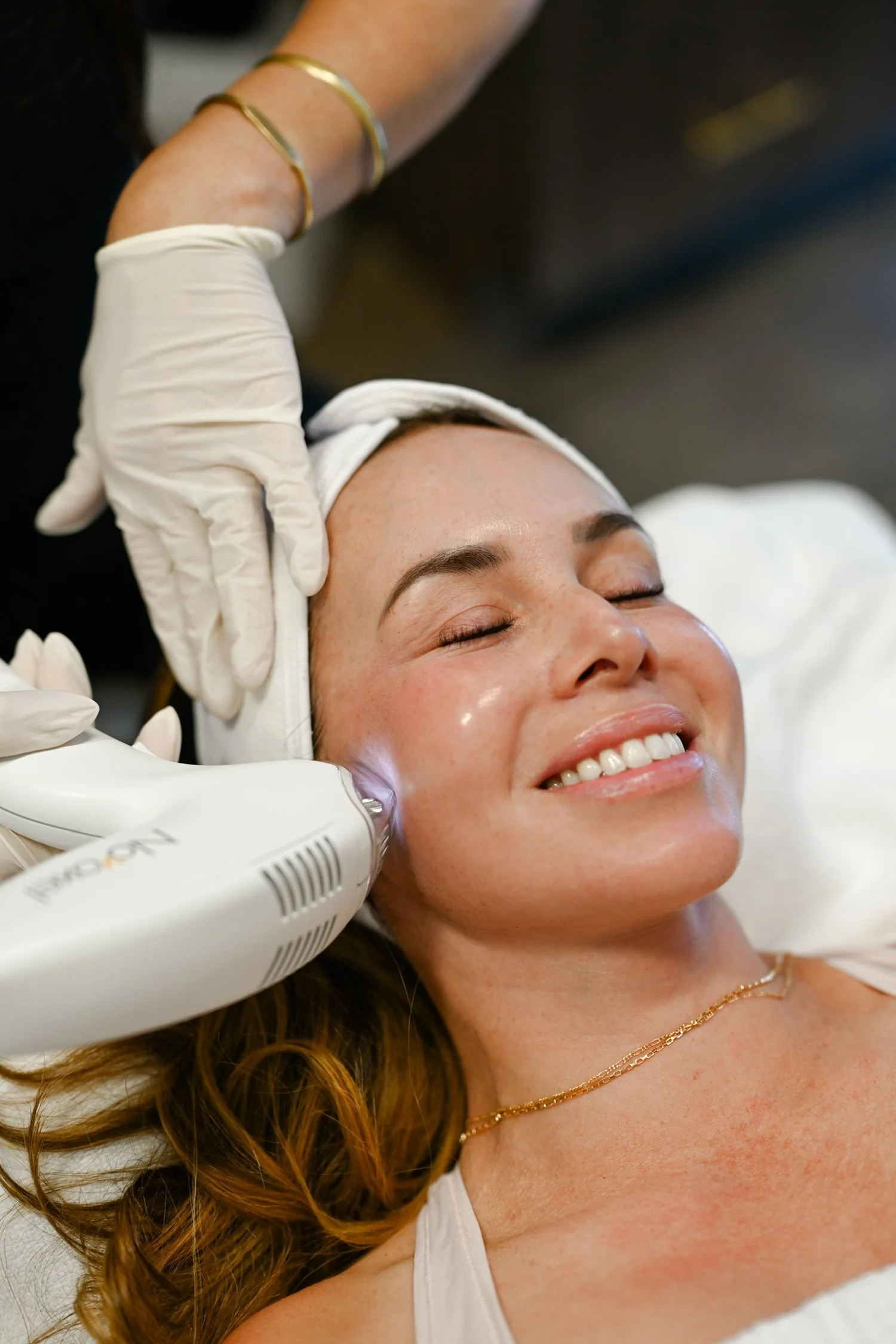 Profesional con guantes aplica un dispositivo de tratamiento estético facial en la mejilla de una mujer durante una sesión práctica. beyouthful